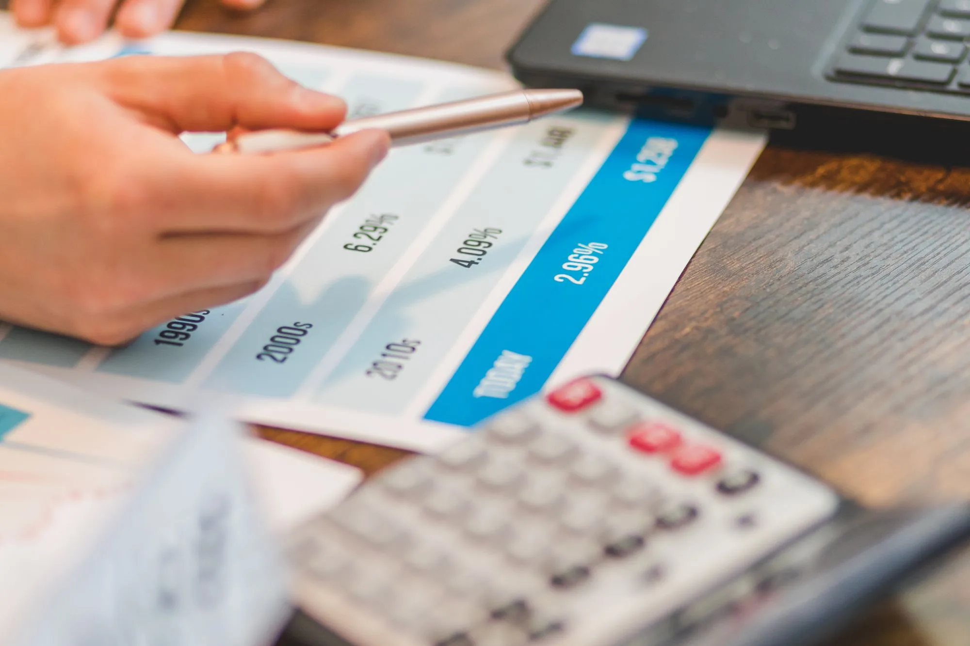 Una mano revisa con bolígrafo y calculadora un cuadro de tipos de interés